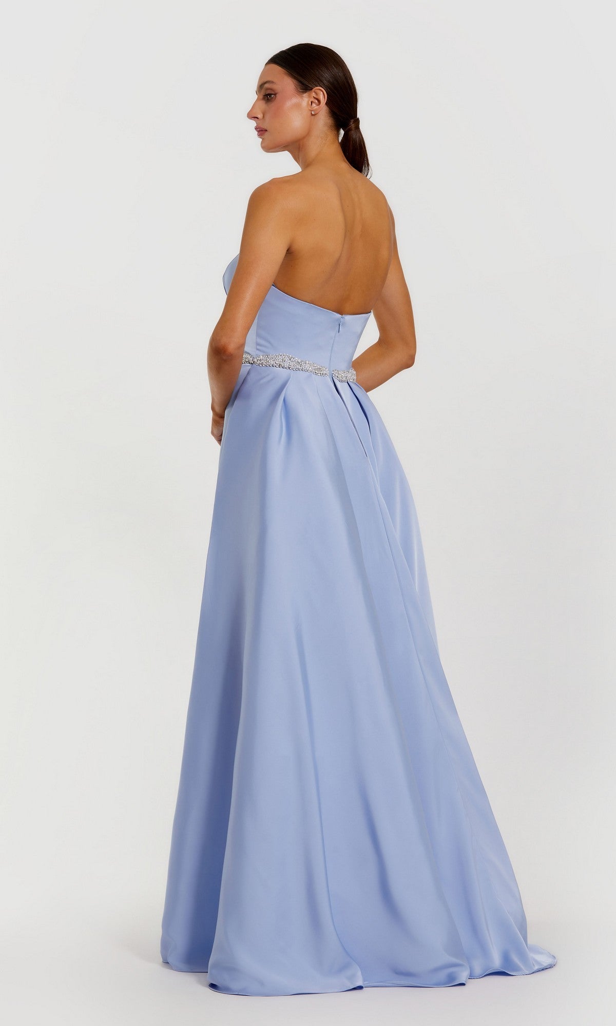 Woman in the Mac Duggal 2317 Long Formal Dress—a light blue satin gown with strapless neckline, fitted waist, and decorative belt—stands against a plain white background.